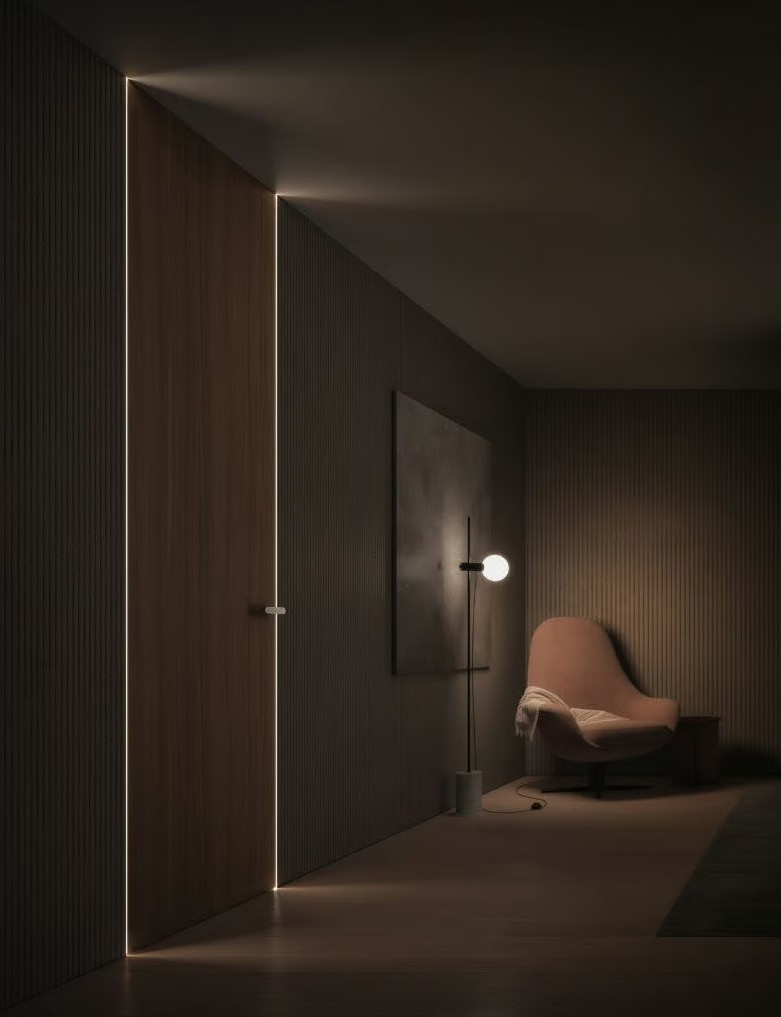 Dark aluminium-wood invisible door integrated into a hotel suite wall