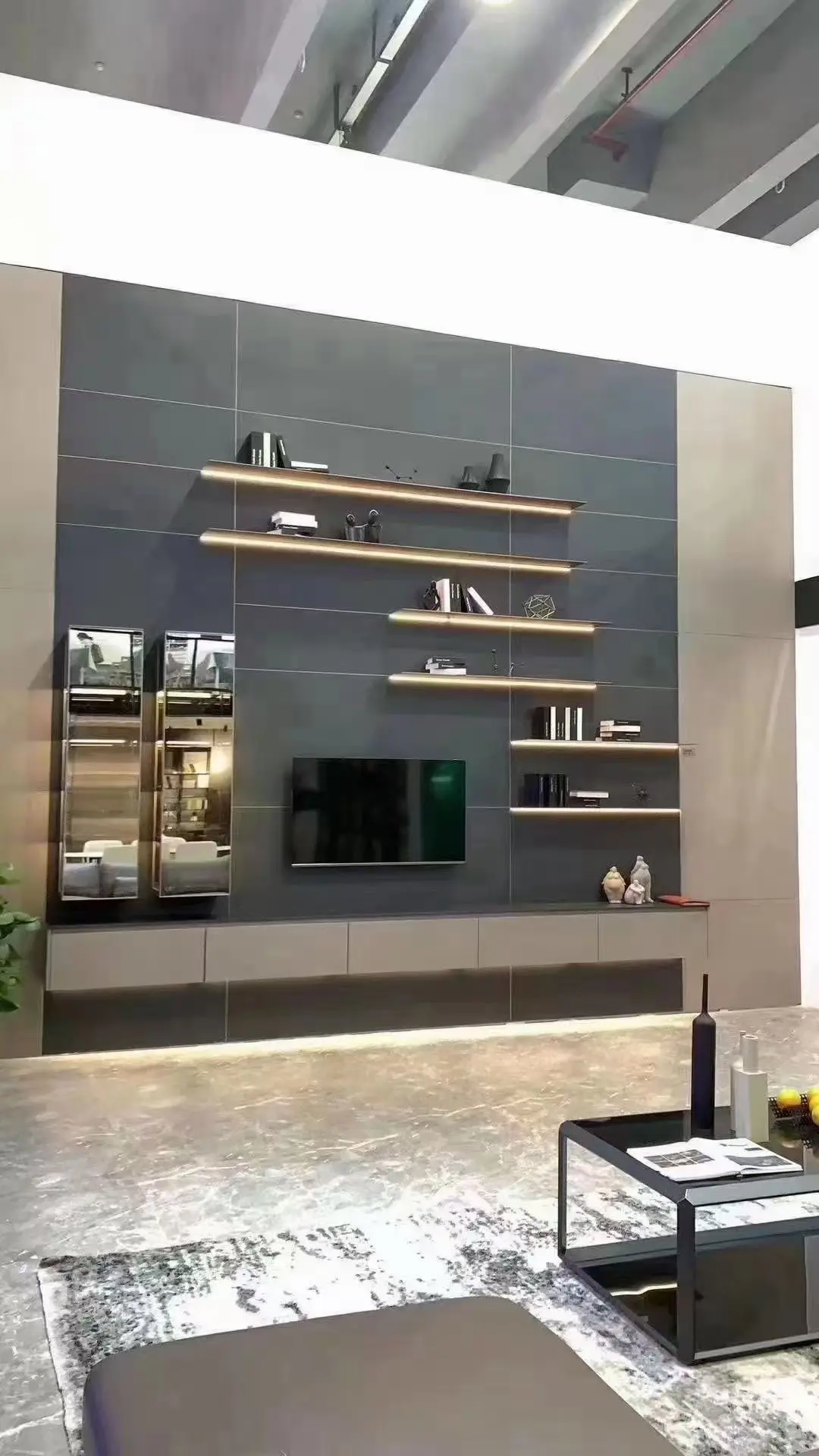 Media wall with staggered illuminated shelves and glass display towers