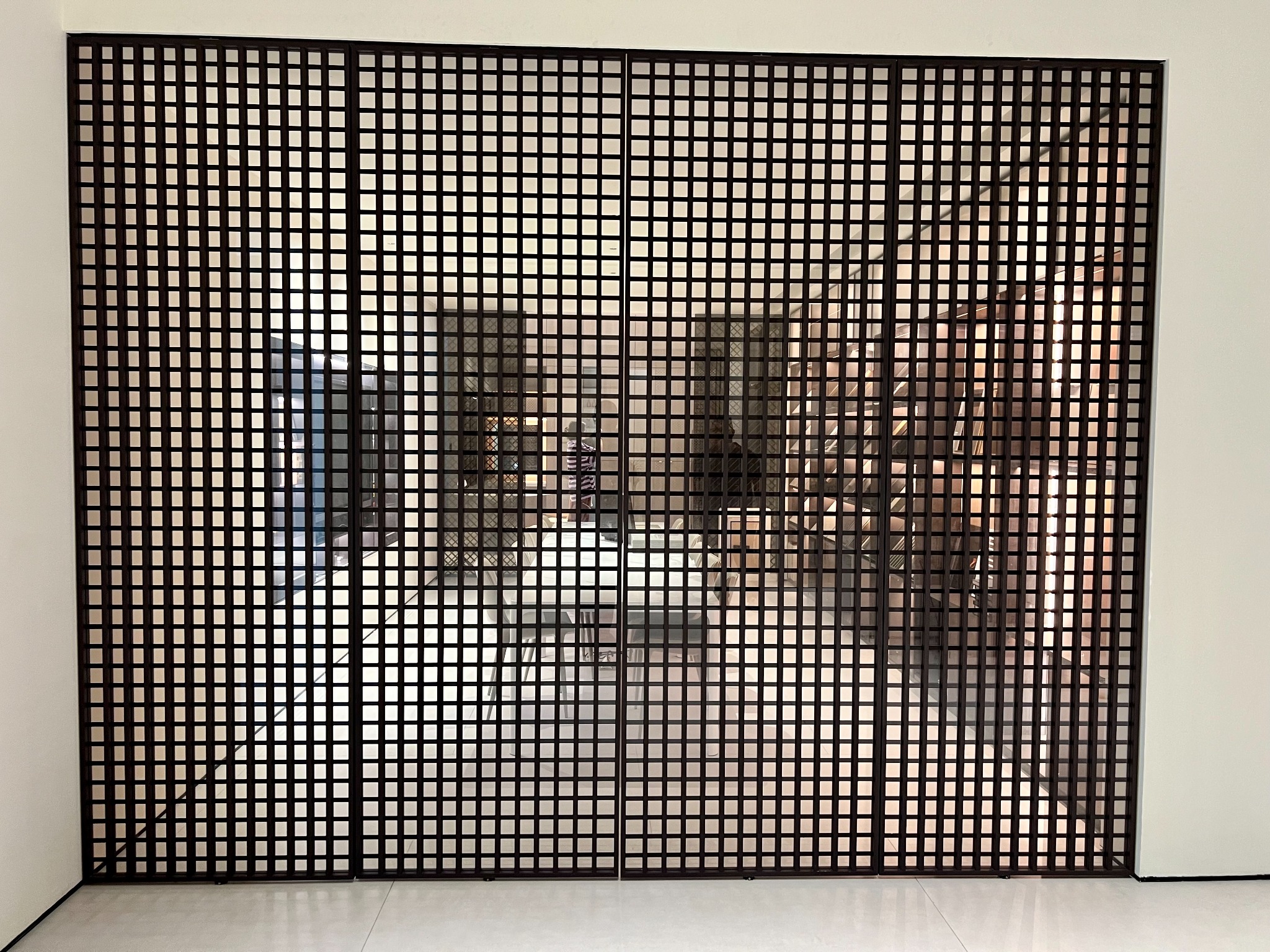Full-height square-grid sliding screen across an interior opening