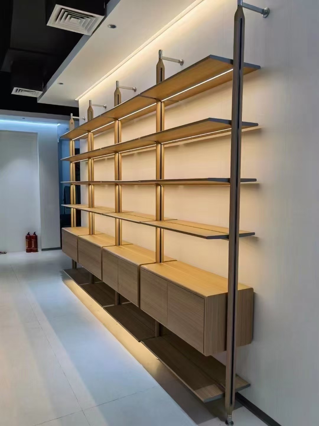 Wall-mounted post shelving with cabinets and integrated lighting