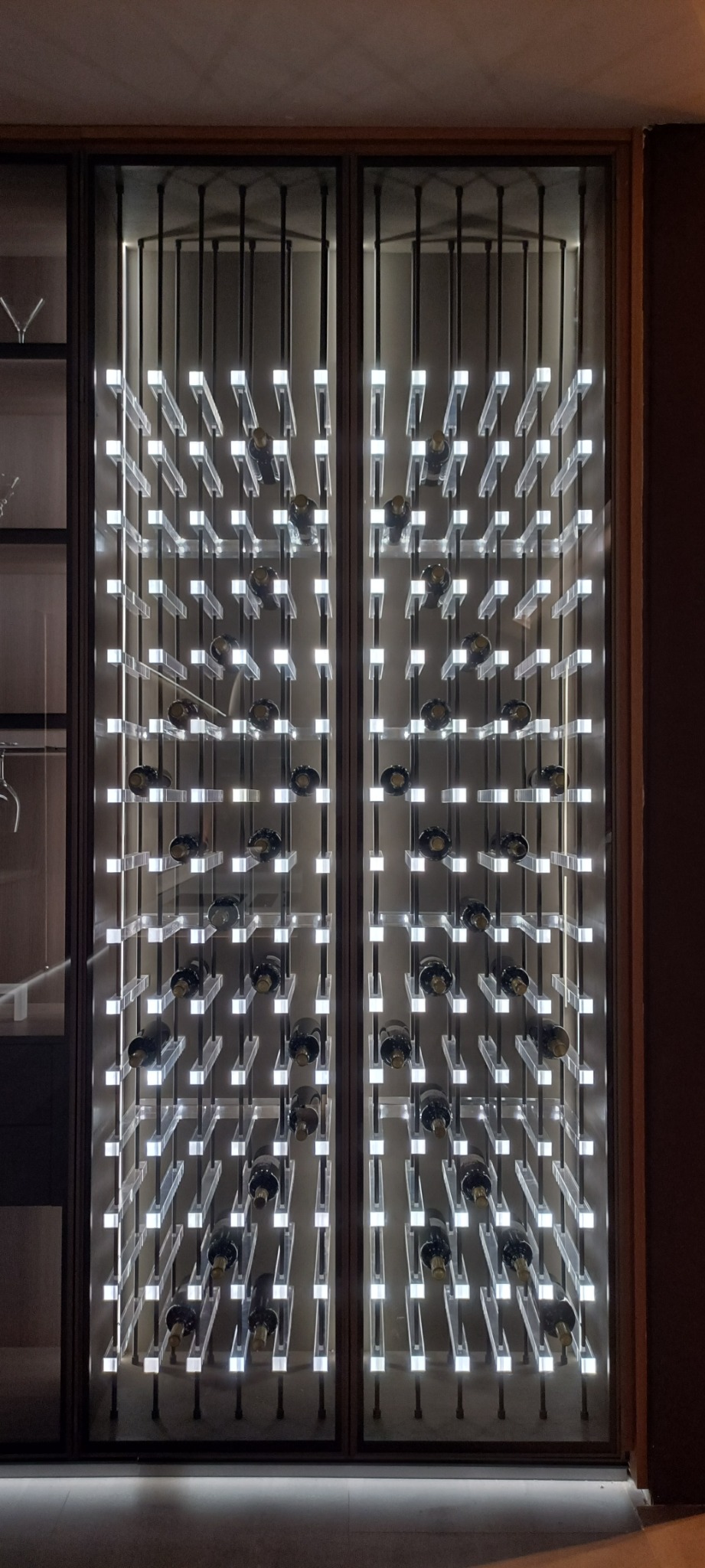 Full-height illuminated wine display behind glass doors